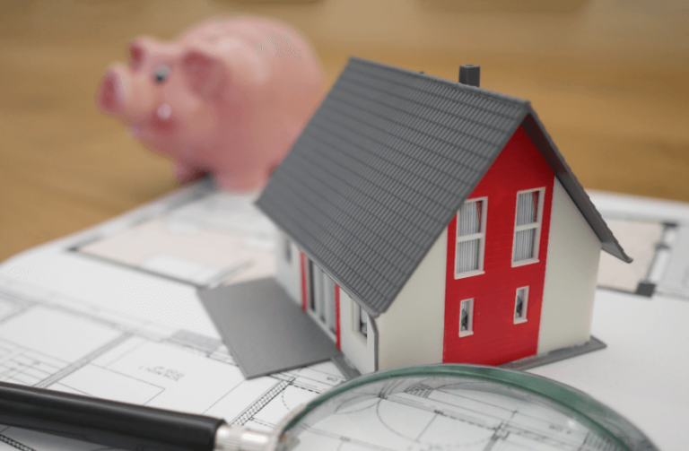 white red paper house with piggy bank on a wooden table